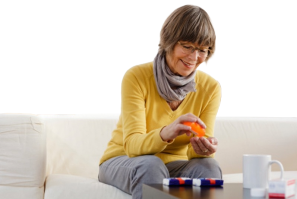 A women sitting on her couch, retrieving a pill from a rx pill bottle. 